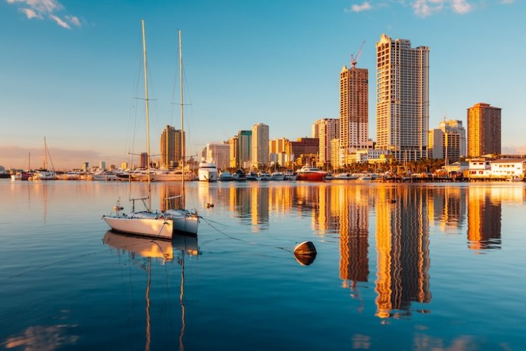 City at sunset with reflective water and a boat